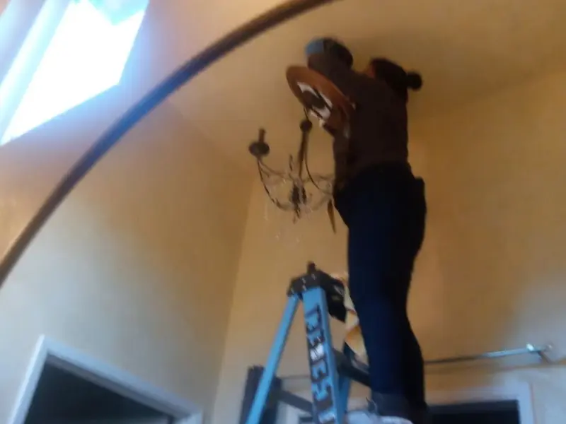 Electrician installing a chandelier in a Ashburn residence